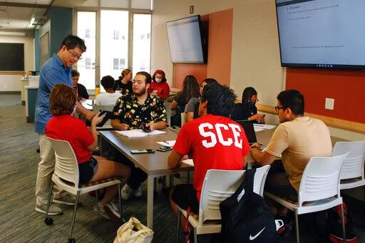 Instructor Oh Moon Kwon, left, speaks to students during a math class, part of an intense six-week summer bridge program for students of color and first-generation students at the University of Wisconsin, in Madison, Wis., July 27, 2022. Seated, in the flowered black shirt is Angel Hope, who said he didn't feel ready for college after online classes in high school caused him fall behind, but says the bridge classes made him feel more confident. Hundreds of thousands of recent graduates are headi