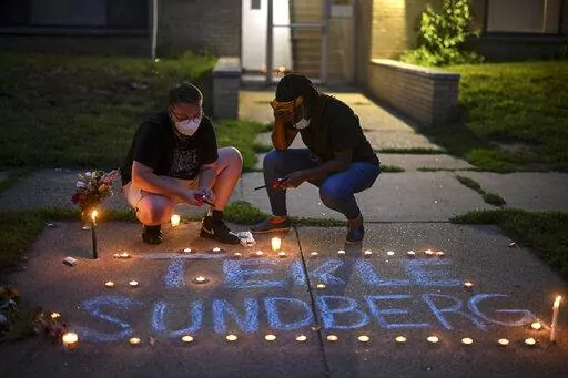 Marcia Howard, activist and George Floyd Square caretaker, right, takes a moment as she lights candles during a vigil for 20-year old Andrew Tekle Sundberg Thursday, July 14, 2022 outside the apartment building where he was killed by Minneapolis Police in Minneapolis. Minneapolis police officers shot and killed Sundberg early Thursday after an overnight standoff that began after he allegedly fired shots inside an apartment building on the city's south side, according to city and state officials.