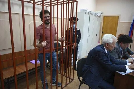 Russian opposition activist and municipal deputy of the Krasnoselsky district Ilya Yashin stands behind bars in a cage during a hearing on his detention, at the Basmanny district court in Moscow, Russia, Friday, Sept. 9, 2022. Yashin, 39, is one of the few prominent opposition figures that refused to leave Russia despite the unprecedented pressure the authorities have mounted on dissent in recent years. (AP Photo/Dmitry Serebryakov)