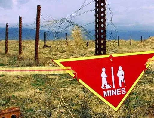 An international sign warning about mines hangs beside a minefield at Bagram Air Base on, March 22, 2002. The White House announced Tuesday a new policy curtailing the use of anti-personnel land mines by the U.S. military, reversing a more permissive stance that was enacted by former President Donald Trump. Under the policy, such explosives will still be allowed to defend South Korea against a potential attack by North Korea, but otherwise they will be banned.  (AP Photo/Mikhail Metzel, File)