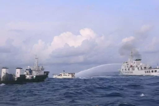 In this handout photo provided by the Philippine Coast Guard, a Chinese Coast Guard ship uses water cannons on Philippine navy-operated supply boat M/L Kalayaan as it approaches Second Thomas Shoal, locally known as Ayungin Shoal, in the disputed South China Sea on Sunday Dec. 10, 2023. The Chinese coast guard targeted Philippine vessels with water cannon blasts Sunday and rammed one of them, causing damage and endangering Filipino crew members off a disputed shoal in the South China Sea, just a