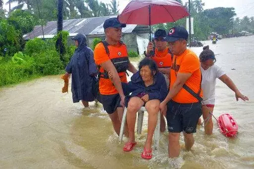 In this photo provided by the Philippine Coast Guard, rescuers evacuate residents from flood waters caused by Tropical Storm Nalgae in Hilongos, Leyte province, Philippines on Friday Oct. 28, 2022. Flash floods and landslides set off by torrential rains left dozens of people dead, including in a hard-hit southern Philippine province, where many villagers are feared missing and buried in a deluge of rainwater, mud, rocks and trees, officials said Saturday. (Philippine Coast Guard via AP)