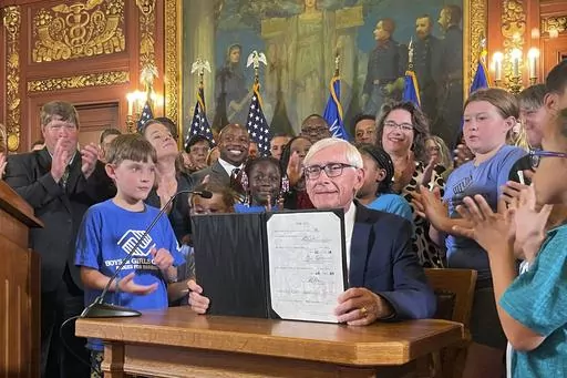 Democratic Wisconsin Gov. Tony Evers displays a two-year budget authored by the Republicans controlled Legislature that he signed, Wednesday, July 5, 2023, in Madison, Wis. Evers used his partial veto power to remove tax cuts for the state's wealthiest taxpayers and protect 180 diversity, equity and inclusion jobs Republicans wanted to cut at the University of Wisconsin. (AP Photo/Harm Venhuizen)