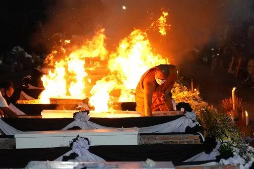 A monk lights funeral pyres to cremate those who died in the day care center attack at Wat Rat Samakee temple in Uthai Sawan, northeastern Thailand, Tuesday, Oct. 11, 2022. A former police officer burst into a day care center in northeastern Thailand on Thursday, killing dozens of preschoolers and teachers before shooting more people as he fled. (AP Photo/Sakchai Lalit)