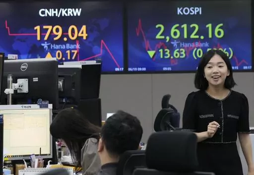 A currency trader passes by a screen showing the Korea Composite Stock Price Index (KOSPI), top right, at the foreign exchange dealing room of the KEB Hana Bank headquarters in Seoul, South Korea, Monday, June 19, 2023. Asian stock markets followed Wall Street lower Monday after the top U.S. and Chinese diplomats agreed to cooperate during a meeting held at a time of friction over an array of conflicts. (AP Photo/Ahn Young-joon)