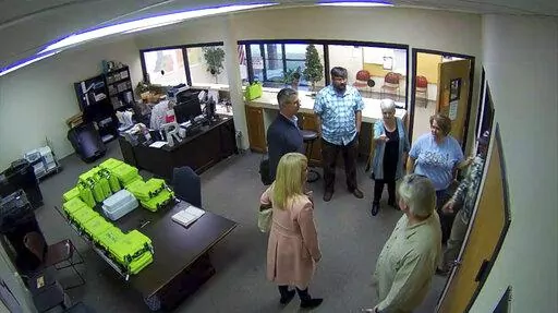 This Jan. 7, 2021, image taken from Coffee County, Ga., security video, appears to show Cathy Latham (center, long turquoise top), introducing members of a computer forensic team to local election officials. Latham was the county Republican Party chair at the time. The computer forensics team was at the county elections office in Douglas, Ga., to make copies of voting equipment in an effort that documents show was arranged by attorney Sidney Powell and others allied with then-President Donald Tr