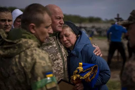 Irina Tromsa, 55, is contorted by comrades of her son Bogdan, 24, a Ukrainian paratrooper from the 95th Brigade killed during fighting against Russian troops in the north-east of the country, during his funeral at the cemetery in Bucha, in the outskirts of Kyiv, on Saturday, April 23, 2022. (AP Photo/Emilio Morenatti)