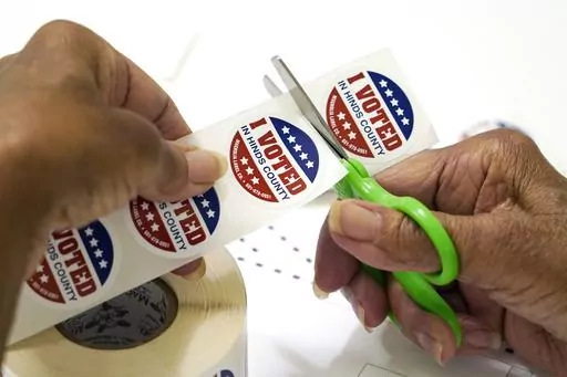 A precinct worker in Jackson, Miss., cuts individual "I Voted in Hinds County" stickers from the roll, Aug. 8, 2023. Poll workers in Hinds County, Mississippi's most populous county, say they still haven't been paid more than a month after the state's primary elections, according to public comments made to the Hinds County Board of Supervisors on Monday, Sept. 18, by poll manager Sheila Davis. (AP Photo/Rogelio V. Solis, File)