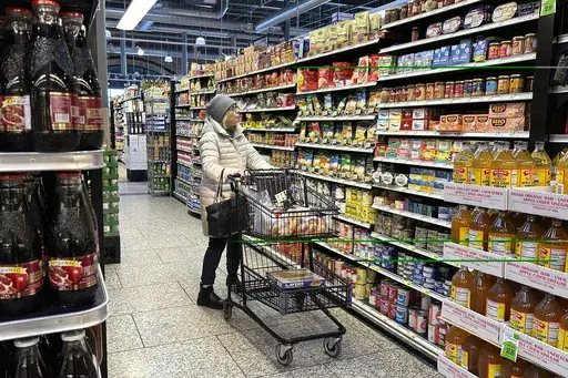 A woman checks prices as she shops at a grocery store in Wheeling, Ill., Friday, Jan. 19, 2024. (AP Photo/Nam Y. Huh)