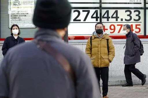 People wearing protective masks stand near an electronic stock board showing Japan's Nikkei 225 index at a securities firm Thursday, Feb. 2, 2023, in Tokyo. Asian stock markets gained Thursday after the Federal Reserve said the U.S. economy is moving toward lower inflation but more interest rate hikes are planned. (AP Photo/Eugene Hoshiko)
