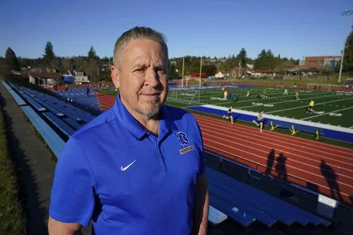 Joe Kennedy, a former assistant football coach at Bremerton High School in Bremerton, Wash., poses for a photo March 9, 2022, at the school's football field. After losing his coaching job for refusing to stop kneeling in prayer with players and spectators on the field immediately after football games, Kennedy will take his arguments before the U.S. Supreme Court on Monday, April 25, 2022, saying the Bremerton School District violated his First Amendment rights by refusing to let him continue pra