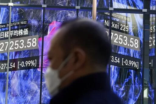 A person stands near an electronic stock board showing Japan's Nikkei 225 index at a securities firm Monday, Dec. 19, 2022, in Tokyo. Asian stock markets fell again Monday as investors wrestled with fears the Federal Reserve and European central banks might be willing to cause a recession to crush inflation. (AP Photo/Eugene Hoshiko)