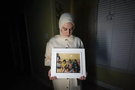 Maryam Kamalmaz hold a photo of her father with some of his 14 grandchildren in Grand Prairie, Texas, Jan. 17, 2024. U.S. officials have developed specific and highly credible intelligence suggesting that Majd Kamalmaz, an American citizen who disappeared seven years ago while traveling in Syria has died, Maryam Kamalmaz said Saturday, May 18. (AP Photo/Julio Cortez, File)