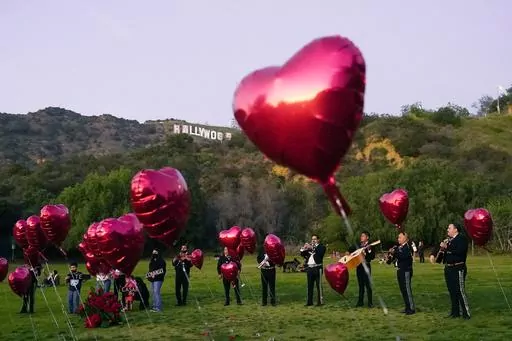 A Mexican Mariachi band surrounded by heart-shaped balloons awaits the arrival of a couple's wedding proposal ceremony at the Lake Hollywood Park in Los Angeles, on Feb. 14, 2022. This is the first Valentine's Day since the U.S. surgeon general issued a public health advisory declaring loneliness and isolation an epidemic with dire consequences. (AP Photo/Damian Dovarganes, File)