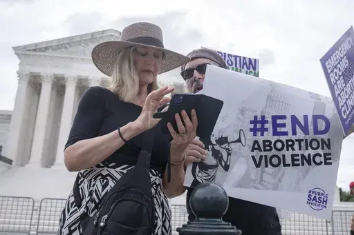 Katie Mahoney, left, and Rev. Patrick Mahoney, chief strategy officer for Stanton Healthcare, an Idaho-based pregnancy center that does not provide abortions, read the text of a Supreme Court decision outside the Supreme Court on Thursday, June 27, 2024, in Washington. The Supreme Court cleared the way Thursday for Idaho hospitals to provide emergency abortions for now in a procedural ruling that left key questions unanswered and could mean the issue ends up before the conservative-majority cour