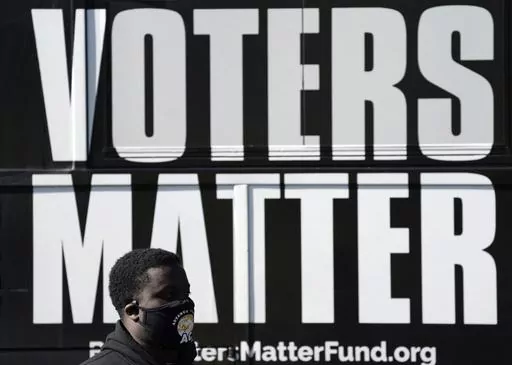 A man wearing a mask gathers with a group in support of Black Voters Matter at the Graham Civic Center polling site in Graham, N.C., Nov. 3, 2020. Some top Democrats are worried that a dip in Black voter turnout, along with other challenges, could doom President Joe Biden and his party in 2024. (AP Photo/Gerry Broome, File)