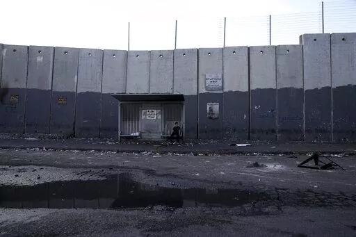 A child sits at a bus stop in the besieged Shuafat refugee camp in east Jerusalem, Thursday, Oct. 13, 2022.It was the site of fierce clashes after Israeli security forces set up checkpoints that choked off the only exit and entry points of the camp during a manhunt following the death of a soldier, bringing life to a standstill for its estimated 60,000 residents. (AP Photo/Mahmoud Illean)