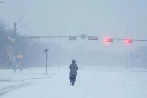 A jogger trots on a snow-covered road during a winter storm, Jan. 15, 2024, in Grand Prairie, Texas. Winter weather brings various hazards that people have to contend with to keep warm and safe. These dangers can include carbon monoxide poisoning, hypothermia and frozen pipes that can burst and make homes unlivable. Public safety officials and experts say there are multiple ways people can prepare themselves to avoid these hazards and keep themselves safe. (AP Photo/Julio Cortez, file)