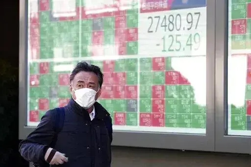 A person walks in front of an electronic stock board showing Japan's Nikkei 225 index at a securities firm Thursday, Feb. 9, 2023, in Tokyo. Shares fell Thursday in Asia after Wall Street gave back some of its recent gains on persisting uncertainty over interest rates and inflation. (AP Photo/Eugene Hoshiko)