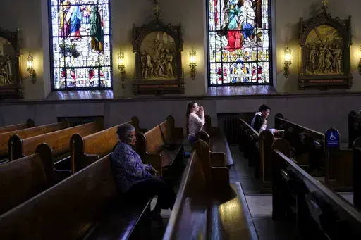 A parishioner prays at St. Peter the Apostle Catholic Church in Reading, Pa., on Sunday, June 16, 2024. Reading is 67% Latino, according to U.S. Census figures, and home to high concentrations of people of Dominican and Puerto Rican heritage — as well as Colombians and Mexicans, who own restaurants and other businesses around town. (AP Photo/Luis Andres Henao)