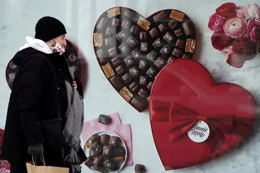 A man passes a Fannie May chocolate shop in downtown Chicago on Valentine's Day, Feb. 14, 2021. Valentine's Day is meant to celebrate romance and the depths of feeling we have for loved ones. So it may be surprising how much Valentine's shopping is done at the last minute. (AP Photo/Nam Y. Huh, File)