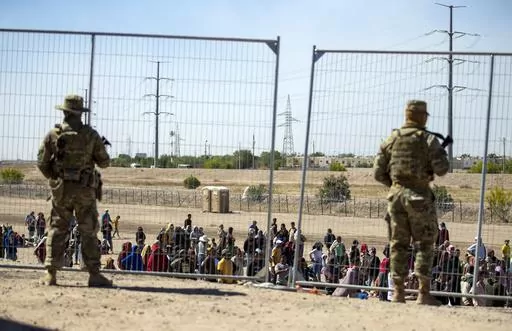 Migrants wait in line adjacent to the border fence under the watch of the Texas National Guard to enter into El Paso, Texas, Wednesday, May 10, 2023. U.S. authorities say an 8-year-old girl died Wednesday, May 17, in Border Patrol custody, a rare occurrence that comes as the agency struggles with overcrowding. The Border Patrol had 28,717 people in custody on May 10, the day before pandemic-related asylum restrictions expired, which was double from two weeks earlier, according to a court filing.