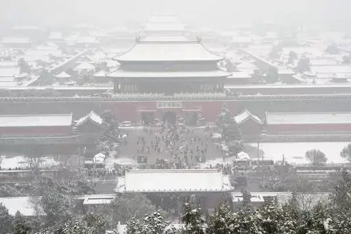 The snow covered Forbidden City is seen from a hilltop pavilion in Beijing, Wednesday, Dec. 13, 2023. Throngs of people in boots and down parkas climbed a hill that overlooks the Forbidden City this week to jostle with others trying to get a shot of the snow-covered roofs of the former imperial palace. (AP Photo/Ng Han Guan)
