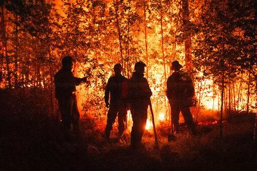 FILE -Firefighters work at the scene of forest fire near Kyuyorelyakh village at Gorny Ulus area, west of Yakutsk, in Russia Thursday, Aug. 5, 2021. A warming planet and land use changes mean more wildfires will scorch large parts of the globe in coming decades. That's according to a UN report released Wednesday, Feb. 23, 2022 that says many governments are ill-prepared to address the problem.  (AP Photo/Ivan Nikiforov, File)