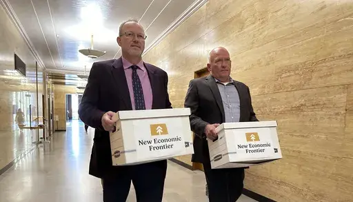 Steve Bakken, left, and Casey Neumann, of the New Economic Frontier ballot initiative group, carry boxes containing petitions to the Secretary of State's Office on Monday, July 8, 2024, at the state Capitol in Bismarck, N.D. (AP Photo/Jack Dura, File)