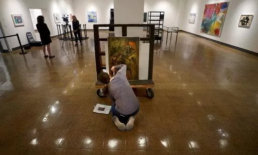 Registrar Kristen Schmidt takes stock of the painting "Seated Man" by Elaine de Kooning, wife of Willem de Kooning, while working on the exhibit Abstract Perspectives in Mid-Century Art, which will display in conjunction with the return of Willem de Kooning's "Woman-Ochre" at the University of Arizona Museum of Art, Tucson, Ariz., Wednesday, Sept. 28, 2022. (Kelly Presnell/Arizona Daily Star via AP)
