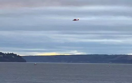 A Coast Guard helicopter searches the area where a floatplane crashed near Whidbey Island, Wash., Sunday, Sept. 4, 2022. (Courtney Riffkin/The Seattle Times via AP)
