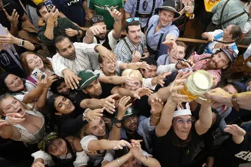 Festival goer reach out for the first glasses of beer at the Hofbraehaus beer tent, on day one of the 189th 'Oktoberfest' beer festival in Munich, Germany, Saturday, Sept. 21, 2024. (AP Photo/Matthias Schrader)