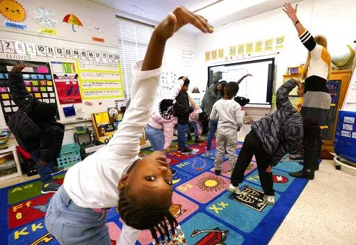First grader Amora Speid, left, stretches out during classes at Chimborazo Elementary School Thursday, Nov. 17, 2022, in Richmond, Va. The Richmond school district, which includes Chimborazo elementary, ultimately decided against year-round school. (AP Photo/Steve Helber)