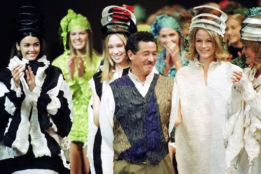 Japanese fashion designer Issey Miyake smiles standing among models after the presentation of his "1993/1994 fall/winter ready to wear collection" on March 17, 1993 in Paris, France. Miyake, who built one of Japan’s biggest fashion brands and was known for his boldly sculpted pleated pieces as well as former Apple CEO Steve Jobs’ black turtlenecks, has died. He was 84. He died Aug. 5, 2022, of liver cancer, Miyake Design Office said Tuesday, Aug. 9. (AP Photo/Lionel Cirroneau, File)