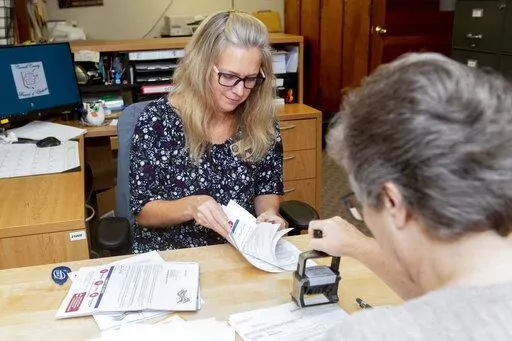 Carroll County Board of Elections Clerk Sarah Dyck, foreground, stamps incoming absentee ballot applications as Elections Clerk Deloris Kean counts more applications at the Board of Elections offices in Carrollton, Ohio, Sept. 26, 2022. (AP Photo/Phil Long)