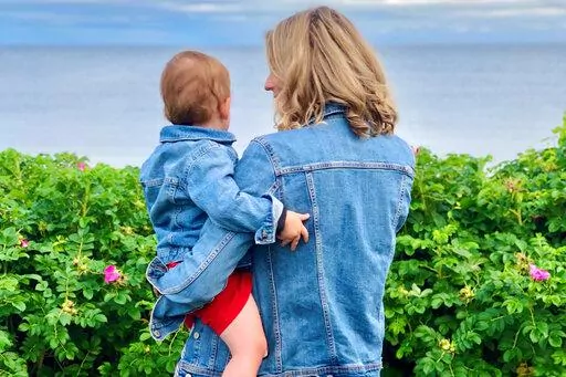 This photo provided by Alex Richer shows his wife, AP writer Alanna Durkin Richer, holding one of their children at Massachusetts' Cape Cod on July 4, 2021. In the aftermath of the May 2022 Uvalde, Texas, school shooting, she writes, "I know rationally that I can’t keep my almost 3-year-old son and his 7-month-old sister in a bubble all their lives. No matter how hard I try, I won't always be able to protect them from harm and pain. But why should I have to fear simply sending them to school?"