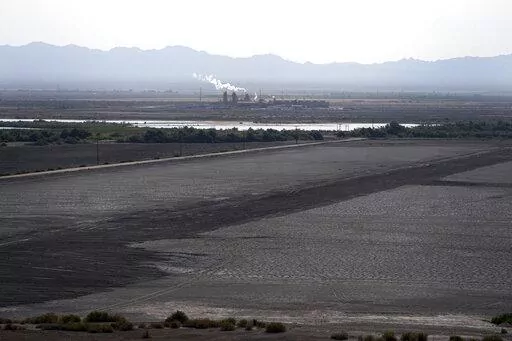 A dried up portion of the Salton Sea stretches out with a geothermal power plant in the distance in Niland, Calif., Thursday, July 15, 2021. Demand for electric vehicles has shifted investments into high gear to extract lithium from geothermal wastewater around the rapidly shrinking body of water. The ultralight metal is critical to rechargeable batteries. (AP Photo/Marcio Jose Sanchez, File)