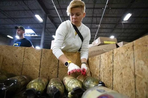 Volunteers with Razom for Ukraine, a New York-based nonprofit, load oxygen tanks into a container as they pack firefighting and medical donations for shipment to Ukraine, Wednesday, Feb. 8, 2023, in Woodbridge Township, N.J. (AP Photo/John Minchillo)