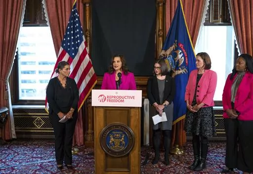 Michigan Gov. Gretchen Whitmer talks with the press before signing the final bill in the Reproductive Health Act on Monday, Dec. 11, 2023, at the Michigan State Capitol building in Lansing, Mich. The bill repeals Michigan's ban on insurance coverage for abortion without the purchase of a separate rider and implements other protections for doctors and patients. (Ryan Garza/Detroit Free Press via AP)