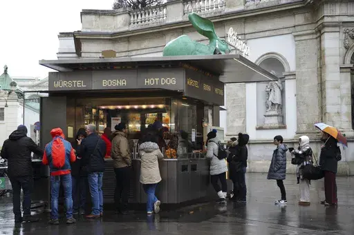 Customers line up at a traditional sausage stand (Wuerstelstand), which are named as intangible cultural heritage by the Austrian UNESCO Commission, in Vienna, Austria, Thursday, Nov. 28, 2024. (AP Photo/Heinz-Peter Bader)