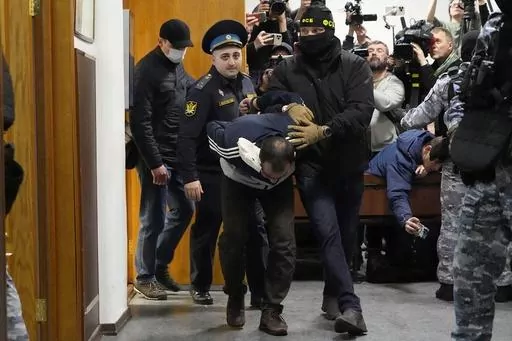 Saidakrami Murodali Rachabalizoda, a suspect in the Crocus City Hall shootings, is escorted by police and FSB officers in Basmanny District Court in Moscow, Russia, on March 24, 2024. The attack on the Moscow concert hall, the bloodiest assault on Russian soil in two decades, appears to be setting the stage for an increasingly harsh response by President Vladimir Putin. Four suspects in the attack appeared in court showing signs of brutal treatment while in custody. (AP Photo/Alexander Zemlianic