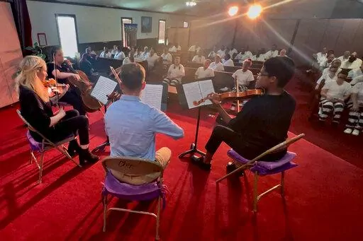 In this video frame grab provided by The Mississippi Department of Corrections, members of a string quartet of First Baptist Church of Jackson perform before inmates at the Central Mississippi Correctional Facility in Pearl, Miss., on Tuesday, July 19, 2022. The musicians included, from right, Noelani Perry, first violinist; Zakary Joyner, second violinist; Rebecca Franklin, viola; and Sarah Beth Mullen, cello. (Leo Honeycutt/The Mississippi Department of Corrections via AP)