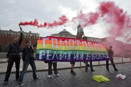 Gay rights activists hold a banner reading "Homophobia -- the religion of bullies" during a protest on Red Square in Moscow on July 14, 2013. (AP Photo/Evgeny Feldman, File)