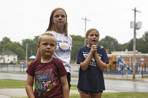 Hudson, 7, left, Callahan, 13, middle, and Keegan Pruente, 10, right, stand outside their school on their first Monday home during the new four-day school week on Monday, Sept. 11, 2023, in Independence, Mo. Hundreds of school systems around the country have adopted four-day weeks in recent years, mostly in rural and western parts of the U.S. Districts cite cost savings and advantages for teacher recruitment. Still, some experts question the effects on students who already missed out on signific