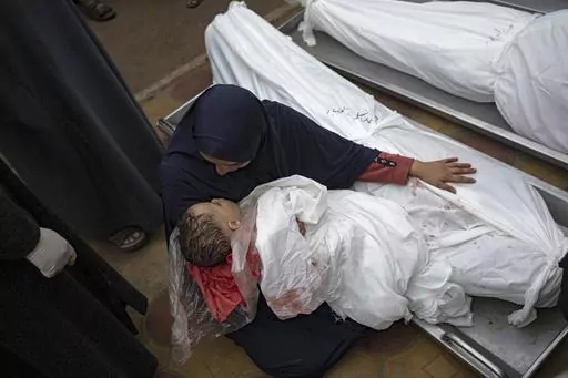 A woman mourns the bodies of her child and her husband killed in an Israeli army bombardment of the Gaza Strip, in the hospital in Khan Younis, Tuesday Dec. 5, 2023. (AP Photo/Fatima Shbair)