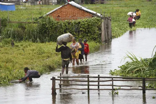 Residents wade through floodwater around their homes after heavy rain in Antananarivo, Madagascar, Jan. 19, 2022, killed at least 10 people. African officials outlined their priorities for the upcoming U.N. climate summit, including a push to make heavily polluting rich nations compensate poor countries for the environmental damage done to them. The continent will also focus on how countries can adapt to global warming and how the continent can best halt further climate-related disasters. (AP Ph
