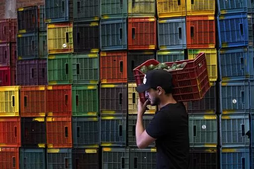 A worker carries a crate of avocados at a plant in Uruapan, Michoacan state, Mexico, Friday, Feb. 9, 2024. A lack of rain and warmer temperatures has resulted in fewer avocados being shipped from Mexico to the United States. (AP Photo/Armando Solis)