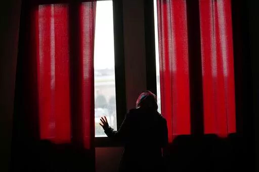 Pakistani-born Iram Aslam, 29, peeks through the window of a local social activities center in Guastalla, northern Italy, Saturday, Feb. 11, 2023, during an interview with The Associated Press. She recounted how she angered her family by refusing a marriage, decided at her birth, to a cousin in Pakistan. Courageous refusal by young immigrant women in Italy to submit to forced marriages sometimes carries a deadly price. In two murder trials this month, Italian prosecutors are seeking justice for 