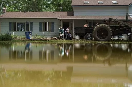 Aileen Rogers, right, and Melody Murter help clean out a friend's house badly damaged by the severe flooding in Fromberg, Mont., Friday, June 17, 2022. (AP Photo/David Goldman)