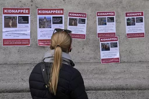 A woman watches posters pasted by the UEJF (Union of Jewish French Students) Monday, Oct. 16, 2023 in Paris. The images across Paris show of Jewish missing persons held by Hamas in Gaza. (AP Photo/Michel Euler)